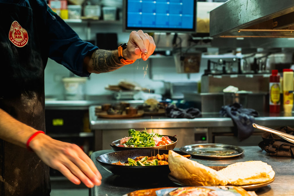 Kok die in een open keuken een gerecht afmaakt