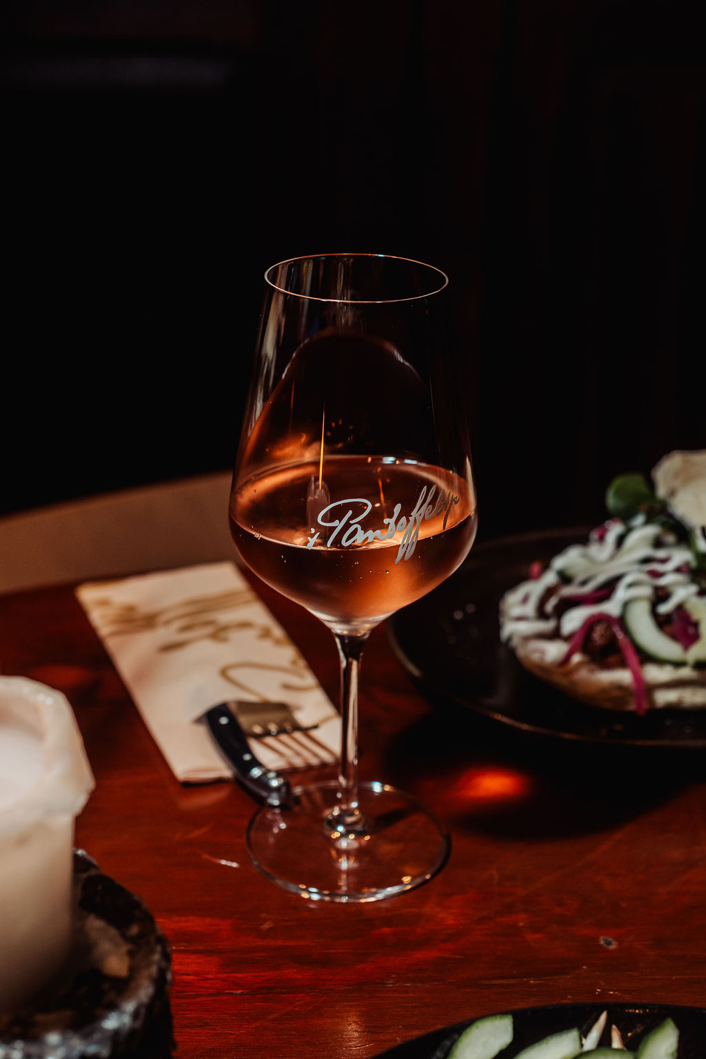 Glas rosé met een gegraveerd logo op een donkere tafel